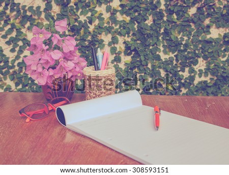 Pens boxes, notebooks and flower vase on a wooden table, Vintage style.