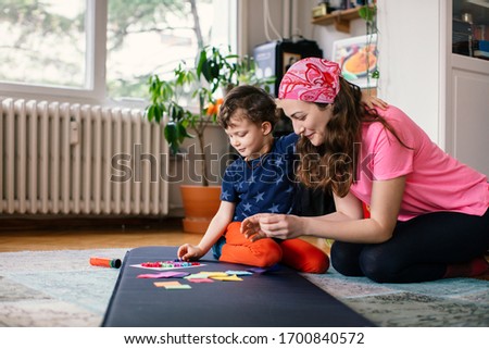 Young Mother and Child Making Paper Handicrafts Together at Home Stockfoto © 