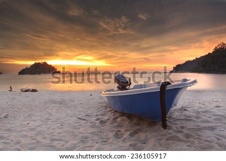 Blue fishing boat at sunset on the beach in Malaysia
