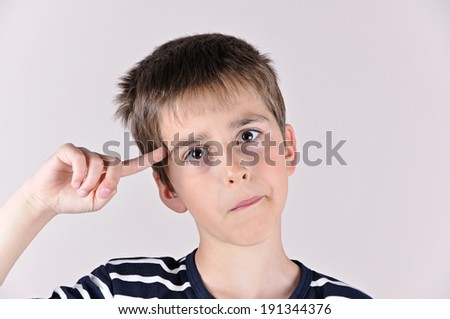 Young boy with the index finger on his head showing you that you are crazy and out of your mind