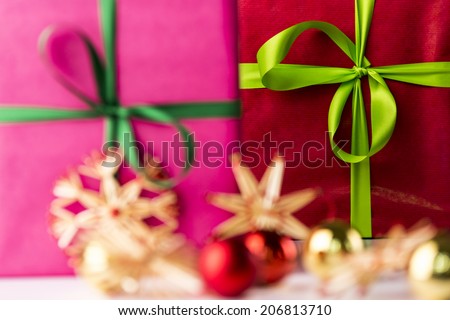 Two bowknots, stars and spheres.  An emerald ribbon and crimson box in the background contrasting with the soft shapes of a magenta gift, straw stars and baubles in the front.
