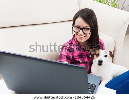 Beautiful woman using laptop computer with pet dog in lap