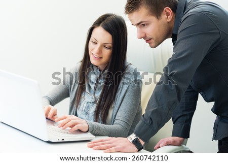 Young business woman working together with her colleague on laptop in office