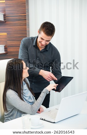 Smiling businesspeople pointing at the touchpad pc in the office