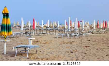 beach umbrellas and sunbeds are on empty beach without people