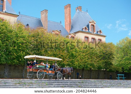 FONTAINEBLEAU, FRANCE - OCTOBER 6, 2013: Horse-drawn carriage with tourists in front of the royal hunting castle Fontainbleau. Palace of Fontainebleau is a UNESCO World Heritage Site.