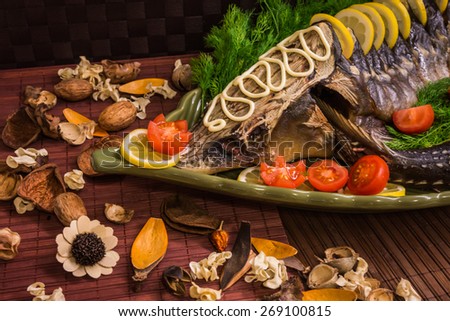 Image of a sturgeon decorated with lemon and tomatoes on a green plate