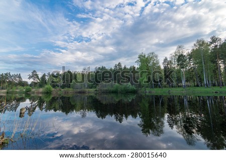 Evening landscape on a pond with wood reflexion in water, Russia, Ural Mountains
