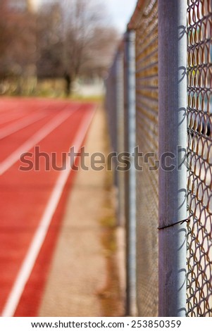 up-close view of chain link fence surrounding a track field separating the road and pedestrians with a retro instagram filter (shallow depth of field)