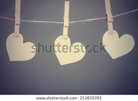 three identical heart wood shapes hanging from clothes pins with a instagram filter (shallow depth of field)