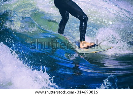 male surfer riding a wave on a white water river park with a retro toned instagram filter
