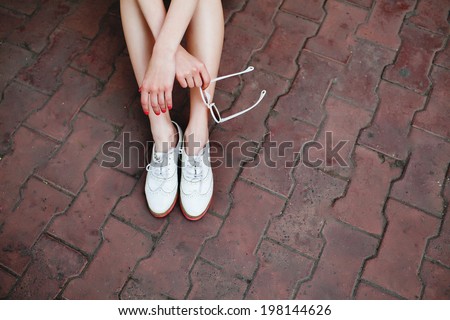 feet with retro shoes  on the floor. Stylish girl holding glasses.