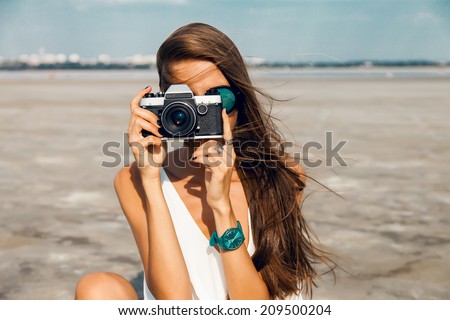 Hipster woman taking photos with retro film camera on the field.