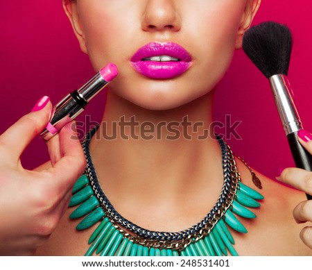 Colorful fashion beauty portrait of model with  bright make up , big pink  full lips and effect necklace .Beautiful young female getting her make-up done against color background.