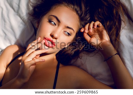 Sexy woman with amazing blue eyes and full lips lying   on pillow in her bedroom.