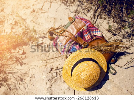 Summer beach accessories  on the send background. Straw hat and colorful backpack
  on the seaside. Warm   colors, sunrise  tropical mood.