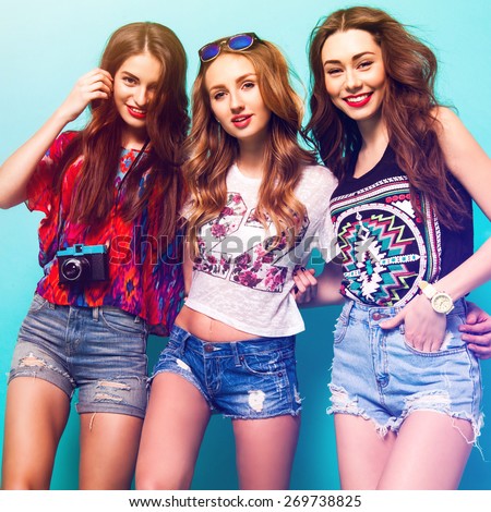 Group of pretty young women\'s in trendy summer  clothes posing in studio against blue background. Three pretty woman smiling and wolfing together. sunny summer colors.