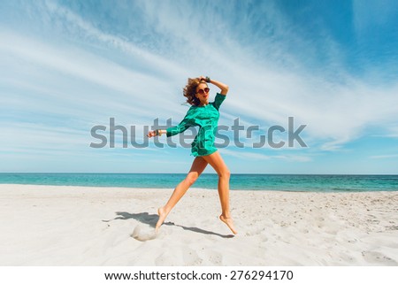 Perfect tan slim sexy woman runs along the  tropical  beach.   Young blonde woman have fun and enjoying  her summer vacation.