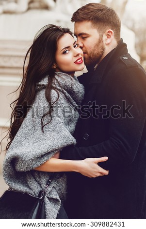 Stylish young couple walking on european autumn streets , have fun and hugging. Wearing trendy season outfit. Creamy  warm colors.