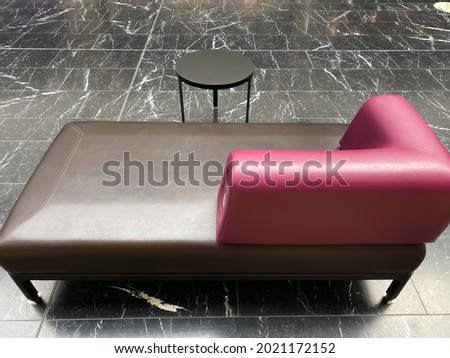 Closeup of one isolated empty purple brown leather chaiselongue with small round table on black and white marble floor (focus on purple sofa part) Stock foto © 