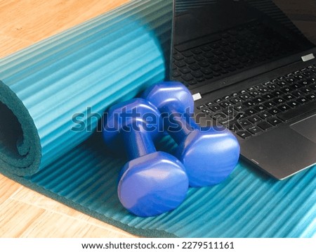 Getting in shape with online training at home. Computer and dumbbells on a yoga mat to work out online. Home gym, body care, healthy lifestyle, remote exercise, sports concept. Foto stock © 
