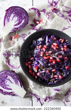sauteed purple cabbage and pomegranate grains  on bowl with raw cabbage on table