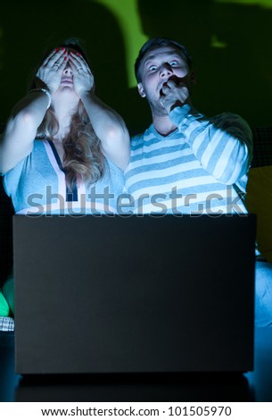 couple is watching scary movie indoors at night
