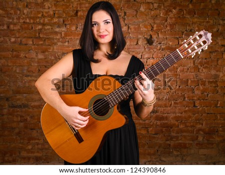 acoustic guitar performer against brick wall