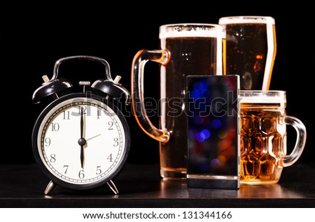 time to drink beer. glasses of fresh lager beer with clock and mobile phone