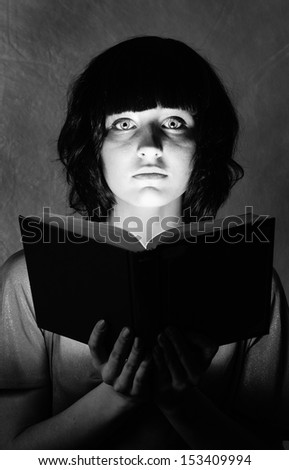 young beautiful woman is illuminated by a glowing book