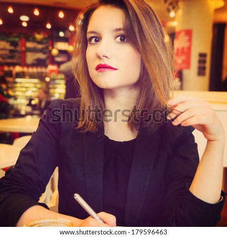 young woman is flirting and writing down her phone number on lip print on serviette in modern cafe