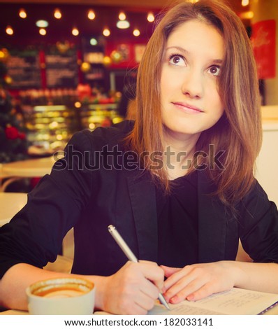 young woman with notebook in modern cafe