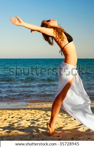 pretty woman reaching to the sky on the sandy beach