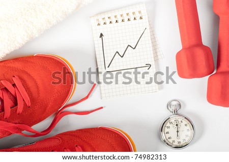 fitness progress. top view of notes, towel, red sneakers, barbells and stopwatch