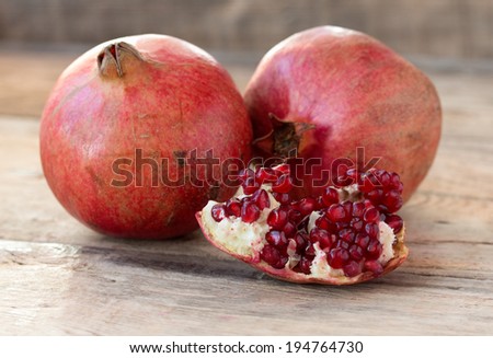 Two red juicy pomegranate on wooden table from old boards