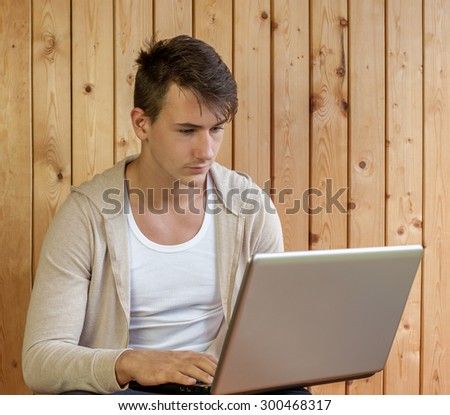 Young modern man using a notebook on old wooden background