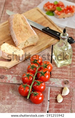 Cherry tomatoes on wooden background with bread, oil and garlic. Selective focus. Shallow depth of field
