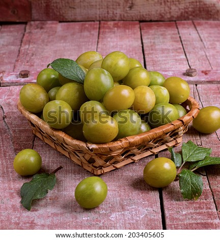 Yellow plums in a basket on wooden background. Selective focus on the plums in the basket