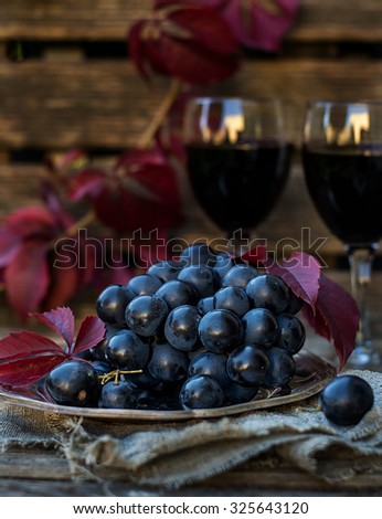 Black table grapes on plate with black wine, rustic style