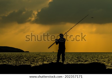 The silhouette of  the man fishing near the sea