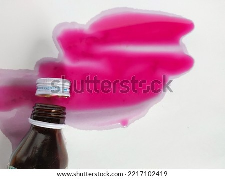 Bottle of syrup medicine with open lid and spilled contents on white background. Stock fotó © 