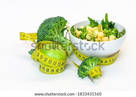 Vitamin-fitness diet, a plate of green salad, a green apple with a centimeter tape. Fresh Food and Roulette, Sports Diet, Raw Food Diet, Ketone Diet Stock foto © 