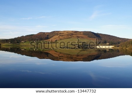 Perfect reflection of a hill in a clear lake with a clear blue sky