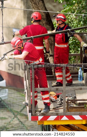 WARSAW, POLAND - AUGUST 31: Tram power grid maintenance works on August 31, 2014 in Warsaw, Poland. Workers in crane basket repair tramway electrification system on 11 Listopada street in Warsaw.