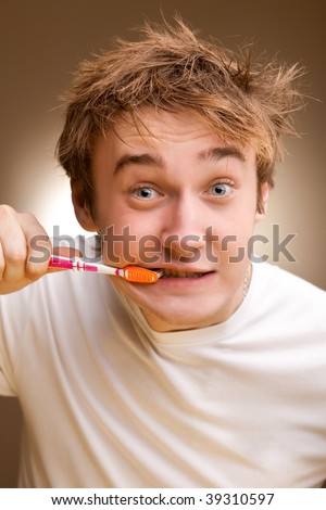 A funny young man cleans teeth. Toned.