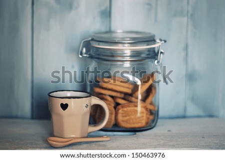 Photo of cute coffee cup with cookies in the jar