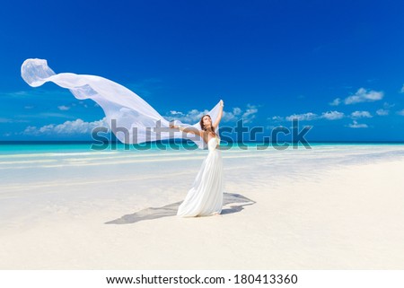 beautiful fiancee in white wedding dress and big long white train, stand on shore sea