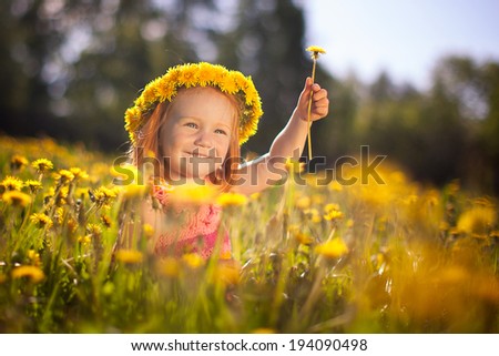 Image of happy child on dandelions field, cheerful little girl resting on dandelions meadow, relaxation outdoor in springtime, vacation.