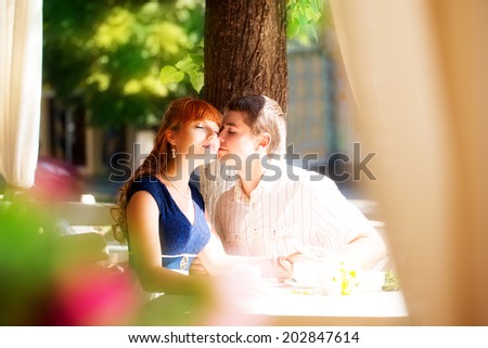 Outdoor portrait of young sensual couple in summer cafe. Love and kiss.