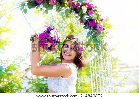 Bridesmaid with a wedding bouquet. Arch for wedding ceremony decorated with flowers in the background. Floristic composition in vintage style. The Provence.